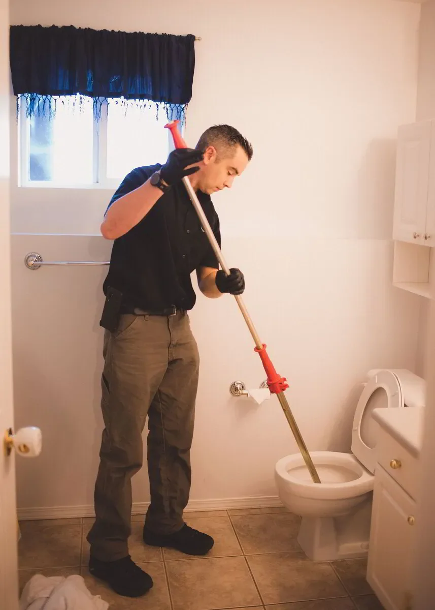 Professional Plumber plunging a toilet