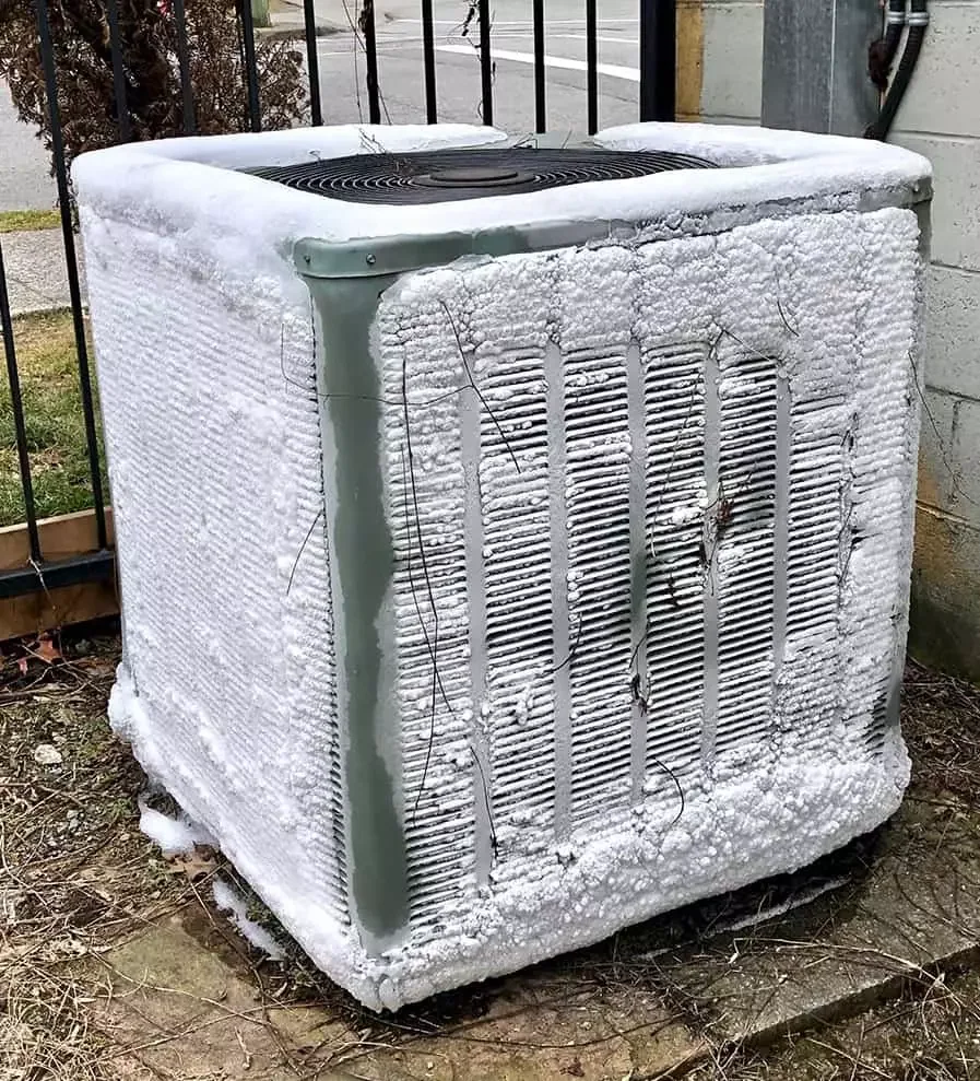 Outdoor heat-pump cabinet heavily covered in white ice